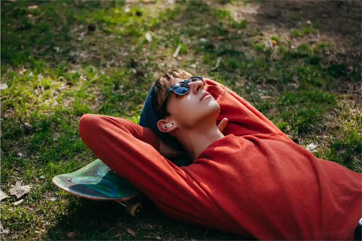 Young man relaxing outdoors while listening to music with JBL true wireless earbuds