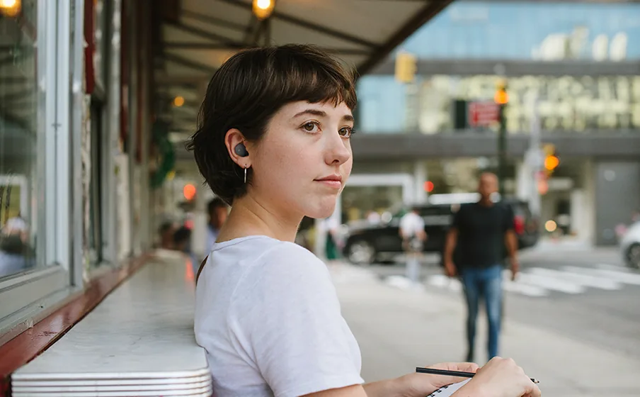 Person relaxing outdoors with JBL Wave Buds 2 using Smart Ambient mode to stay aware of surroundings