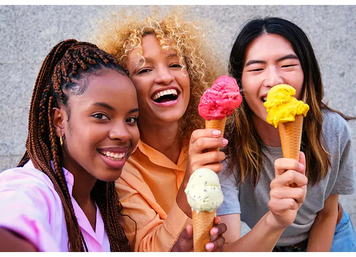 A group of three young people standing close together, smiling and holding ice cream cones while taking a selfie. One of the people is taking the selfie using Galaxy A37 5G's Front Camera for vibrant, sharp photo details.